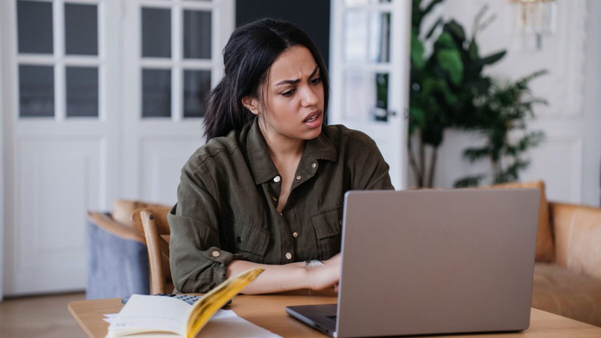 A woman sitting at the table looking at her laptop.