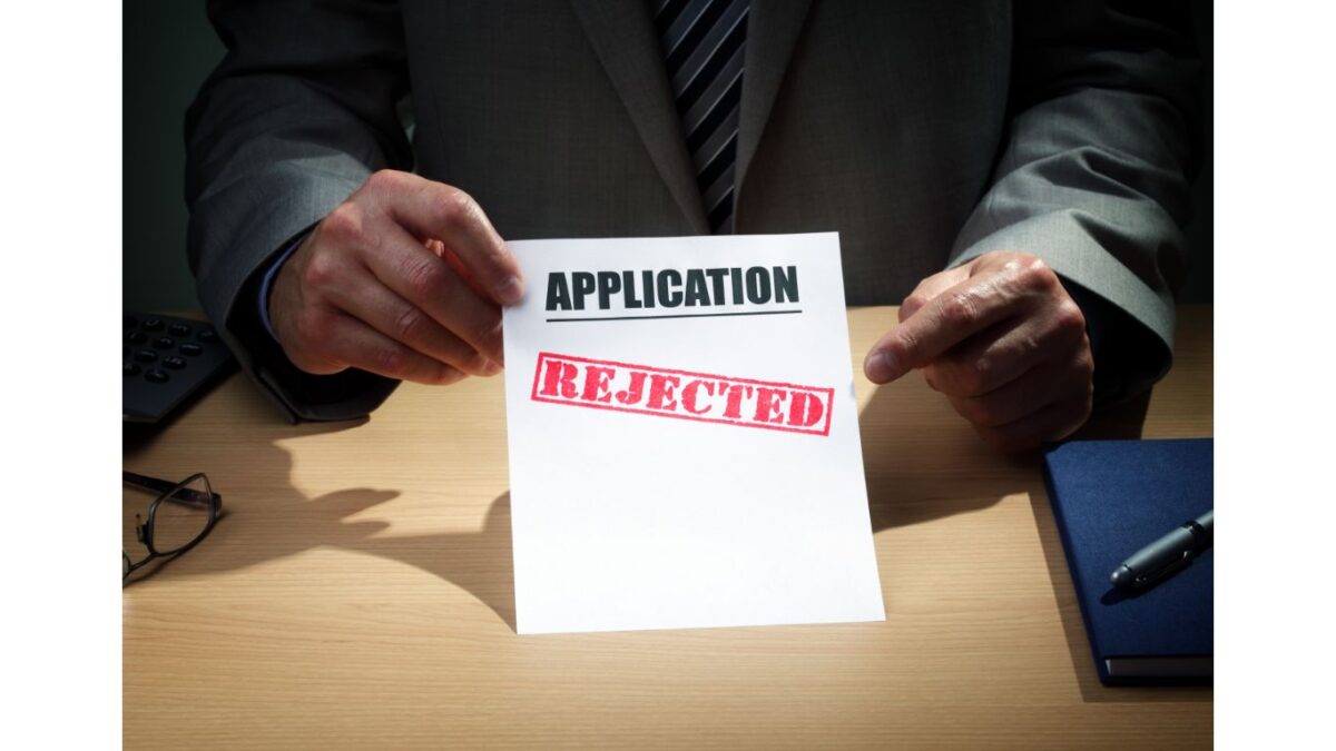 A man holding an application and paper with the word rejected on it.